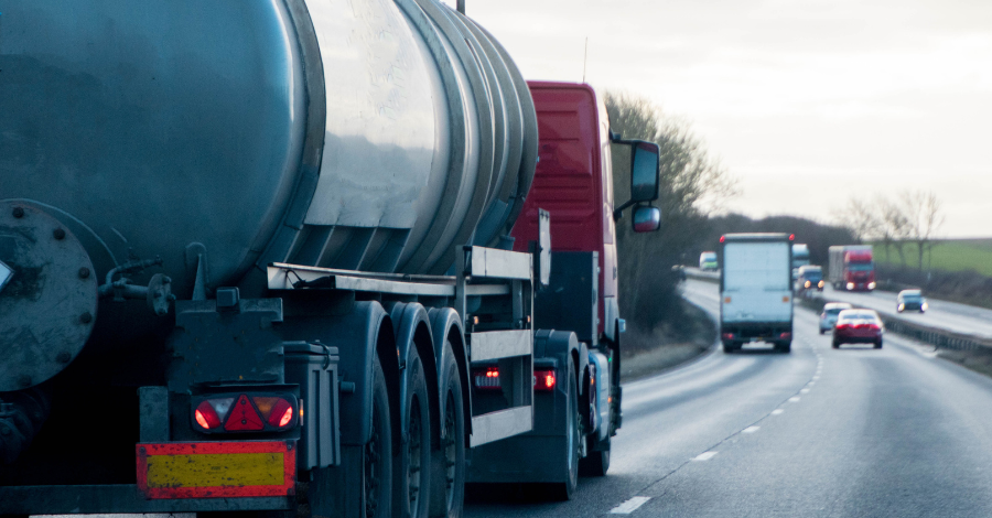 A large HGV driving on the motorway with a large tanker on the back.